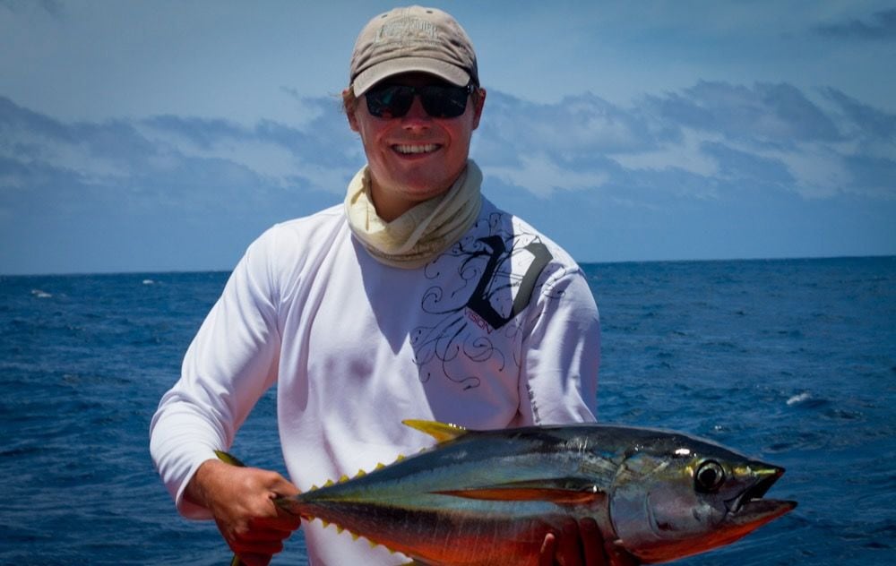 Olli-Mikael Vaittinen holding a yellowfin tuna boatside in tropical blue water