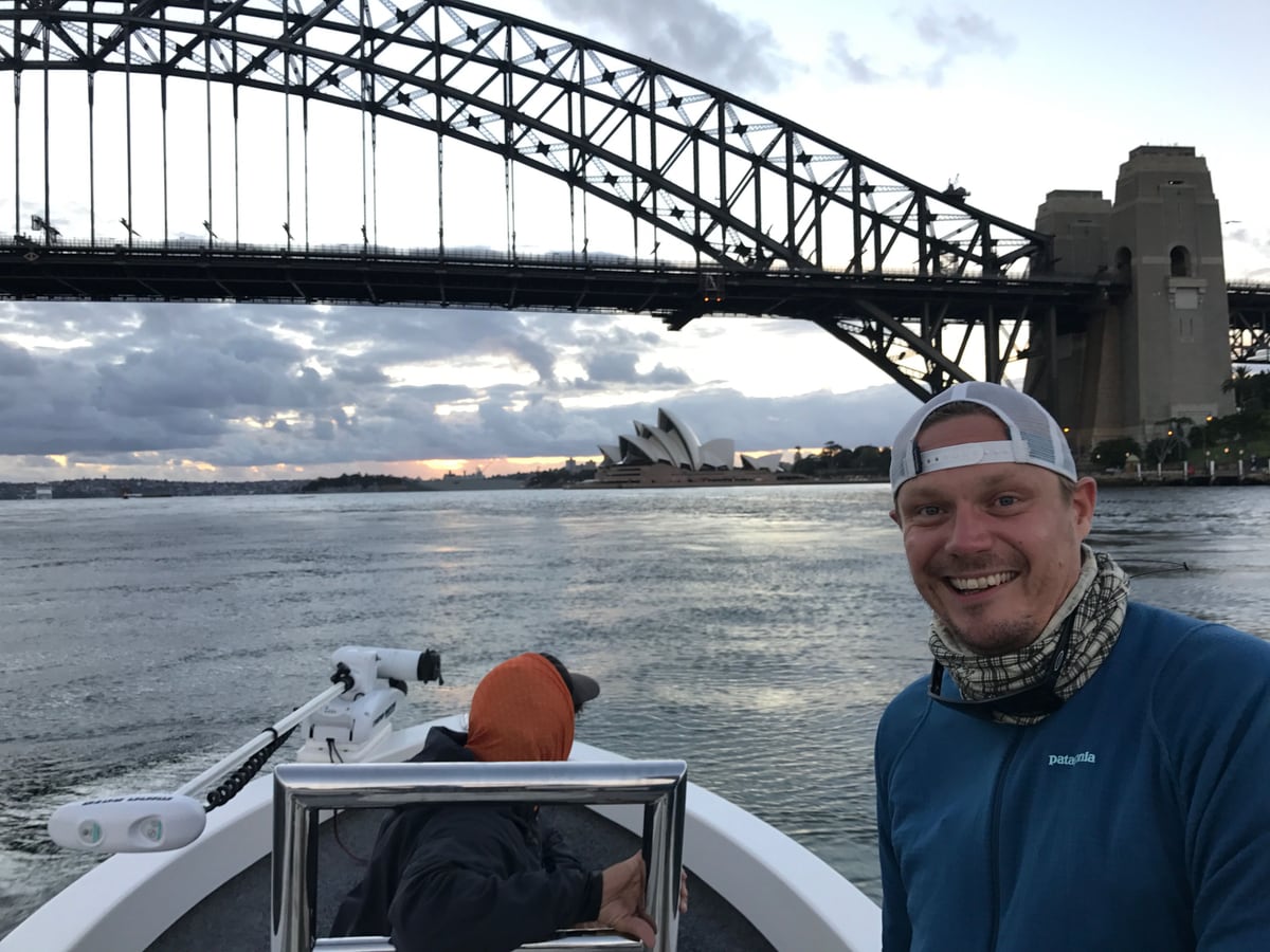 Olli-Mikael Vaittinen on a fishing tinnie under the Sydney Harbour Bridge with the Opera House behind at sunset